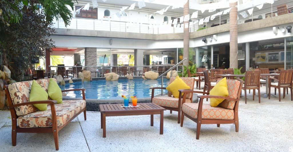 a swimming pool in a hotel with chairs and a table at Hotel Rio Malecon in Puerto Vallarta