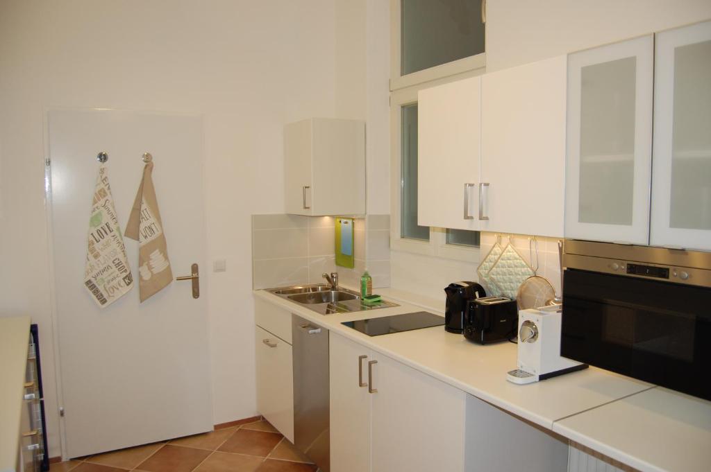 Biała kuchnia z białymi szafkami i zlewem w obiekcie Wiener Ferienwohnung w Wiedniu