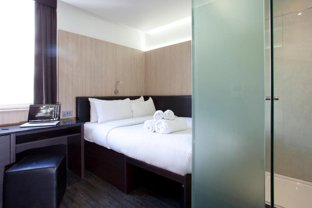 a hotel room with a bed and a desk with a laptop at The Z Hotel Victoria in London