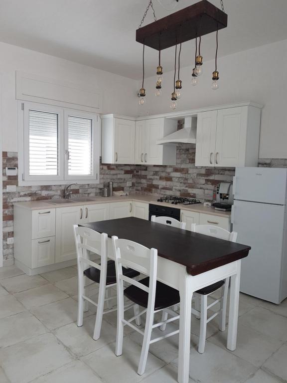 a white kitchen with a black table and white chairs at Lu Salentu White House in Marina di Mancaversa