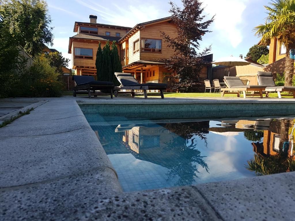 a swimming pool with chairs and a house in the background at B&B de German in Pucón