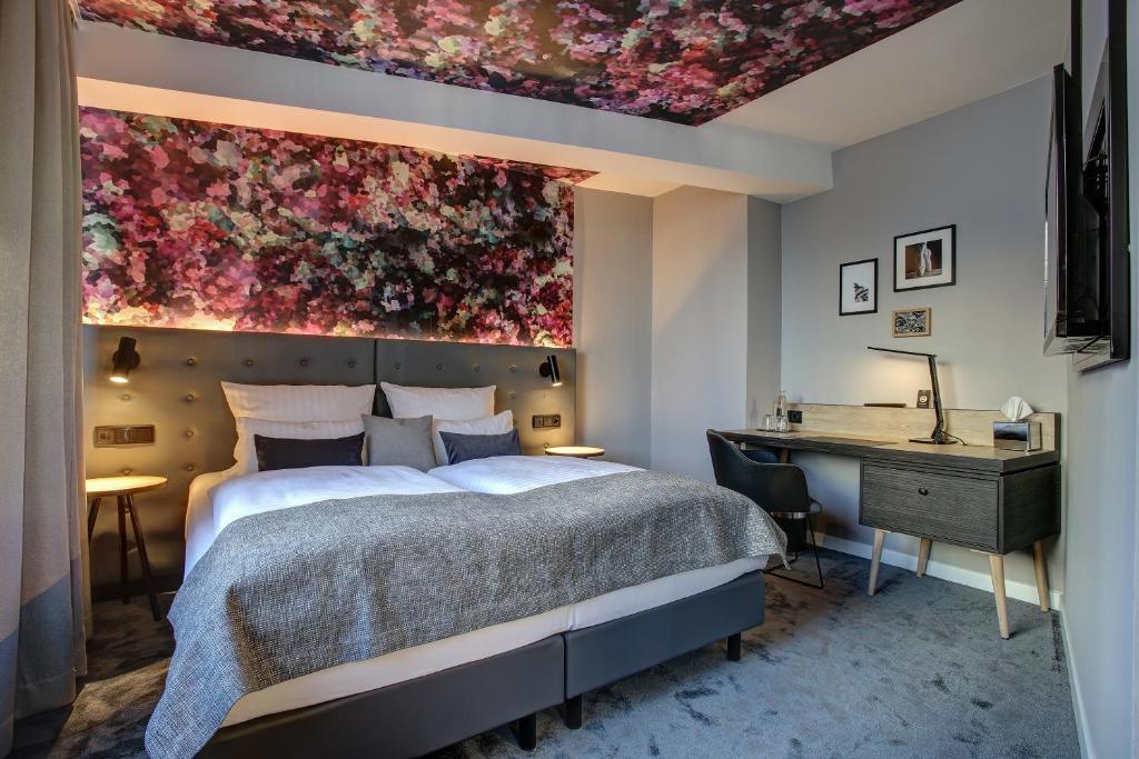 Schlafzimmer mit einem Bett mit Wandgemälde in der Unterkunft NYCE Hotel Hamburg City in Hamburg
