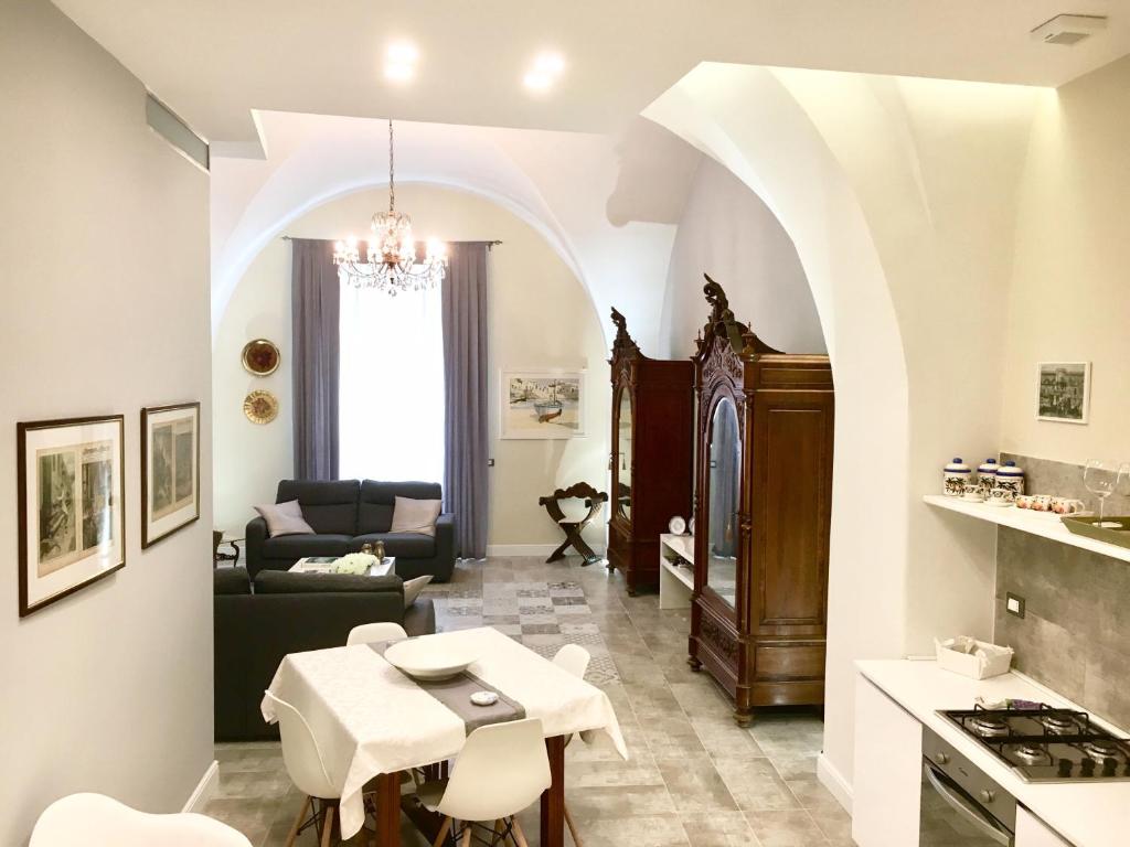 uma cozinha e sala de estar com mesa e cadeiras em Dimora del Papa em Catânia