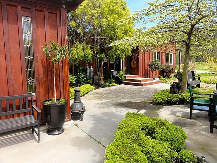 un patio avec un banc à côté d'un bâtiment dans l'établissement Matai Huka Boutique Accommodation, à Paraparaumu