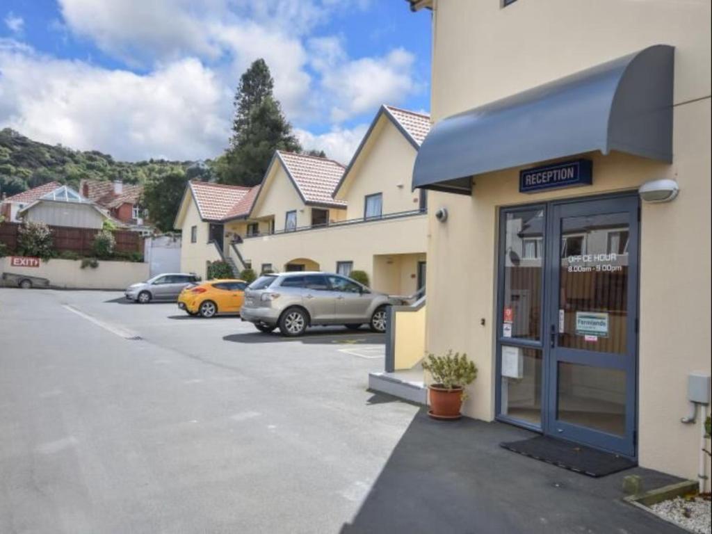un parcheggio con auto parcheggiate fuori da un edificio di Bella Vista Motel Dunedin a Dunedin