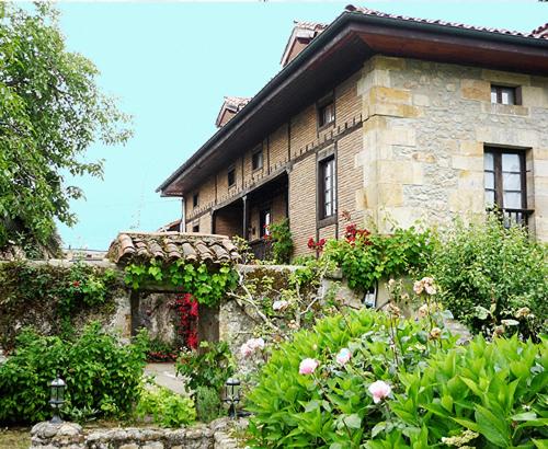 une ancienne maison en pierre avec des fleurs devant elle dans l'établissement Posada Vallejo, à Periedo