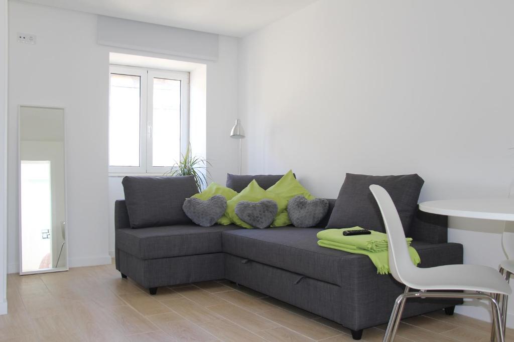 ein Wohnzimmer mit einem grauen Sofa und gelben Kissen in der Unterkunft Oporto Cozy House in Porto