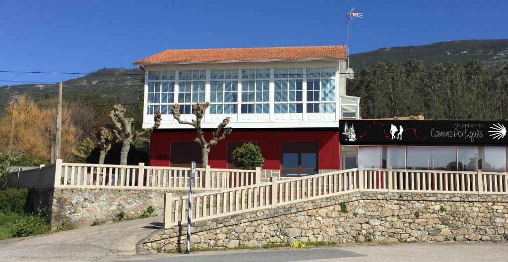 un edificio rosso e bianco con una recinzione bianca di Alojamiento Camino Portugues Oia a Villadesuso