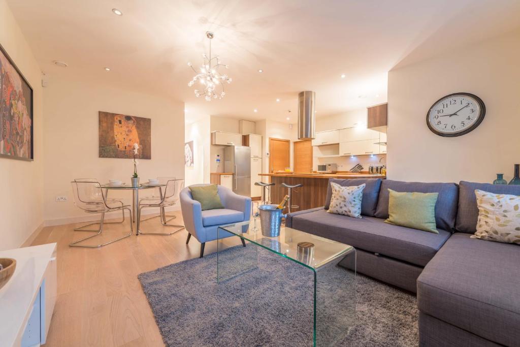 a living room with a couch and a table and a clock at Hampden Apartments - The Catherine in Windsor
