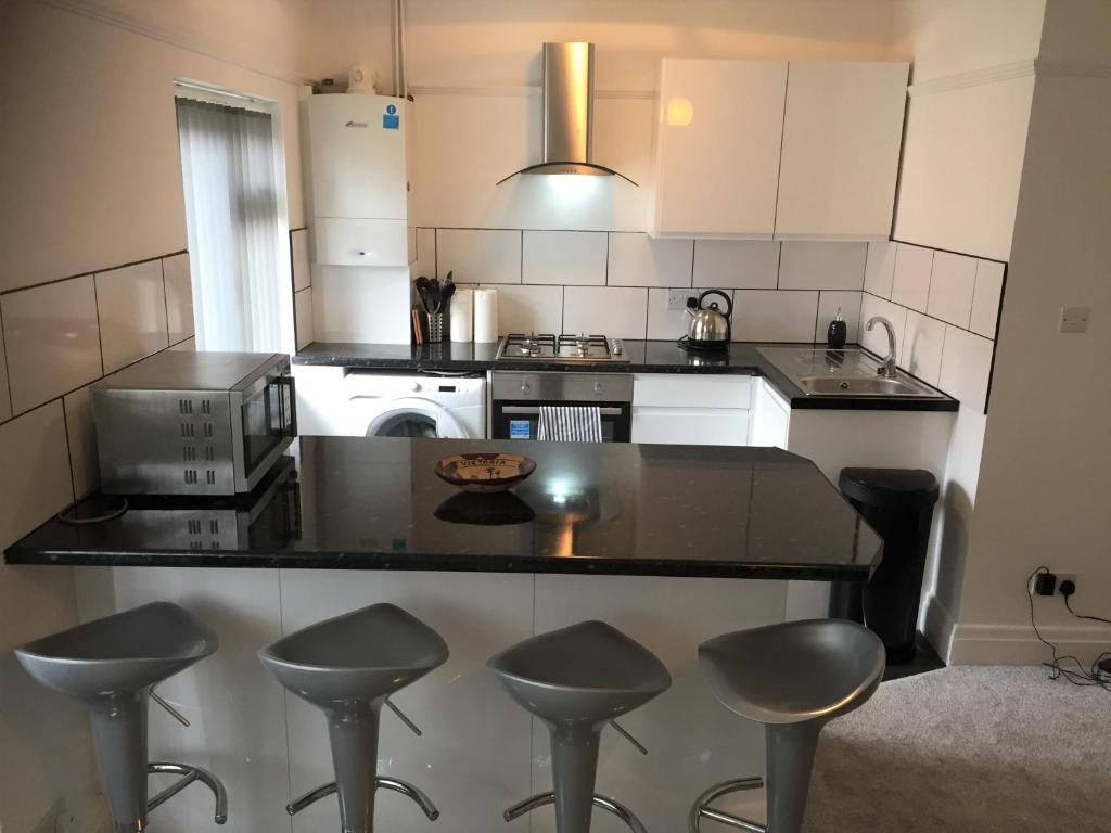 a kitchen with a counter and stools in it at Marine Lake apartment in West Kirby