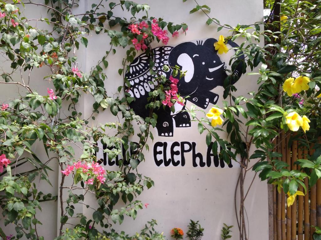 una señal en el costado de una pared con flores en Little Elephant Cottage, en Gili Trawangan