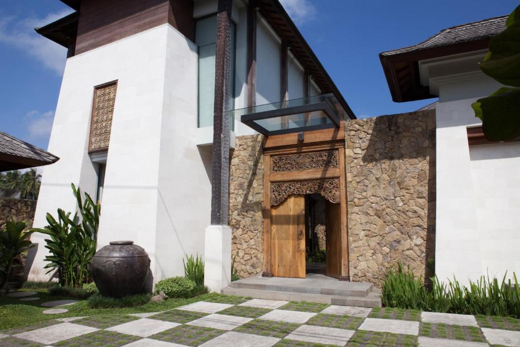 a villa with a wooden door and a courtyard at Swarapadi Villa in Ubud