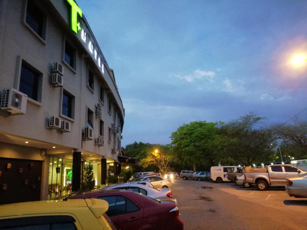 a parking lot with cars parked outside of a hotel at T+ Hotel Sungai Petani in Sungai Petani