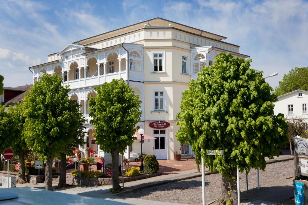 un bâtiment blanc avec des arbres devant lui dans l'établissement Villa Fernsicht - Apt. 04, à Sellin