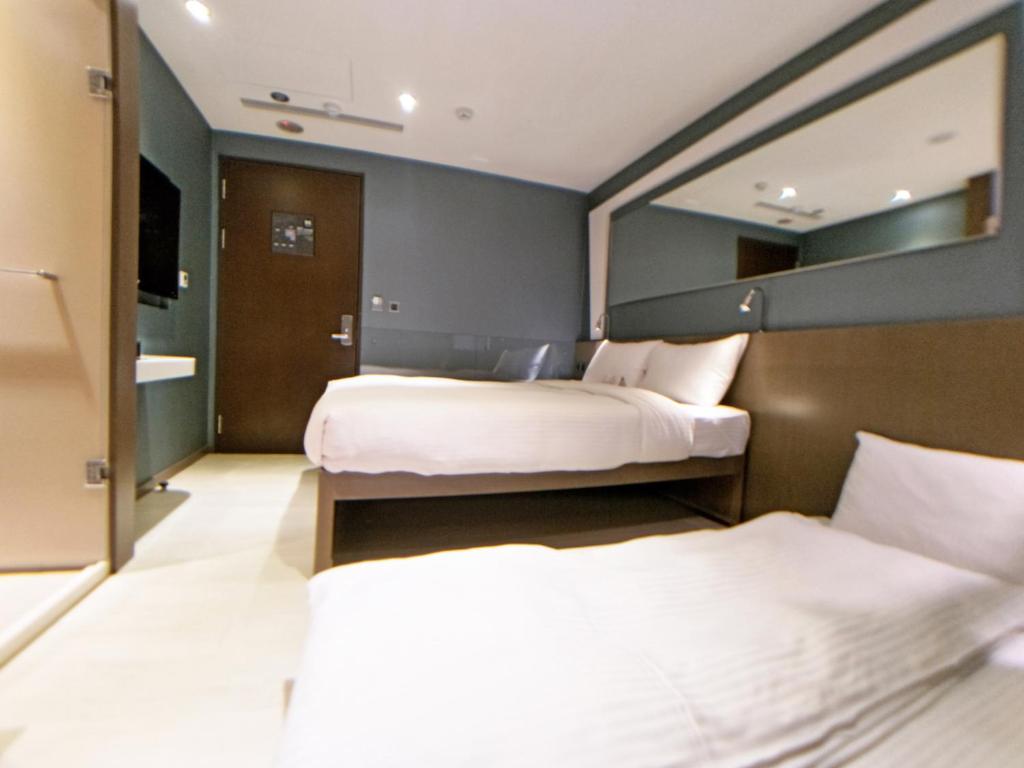 a hotel room with two beds and a mirror at Beauty Hotels Taipei - Hotel B6 in Taipei