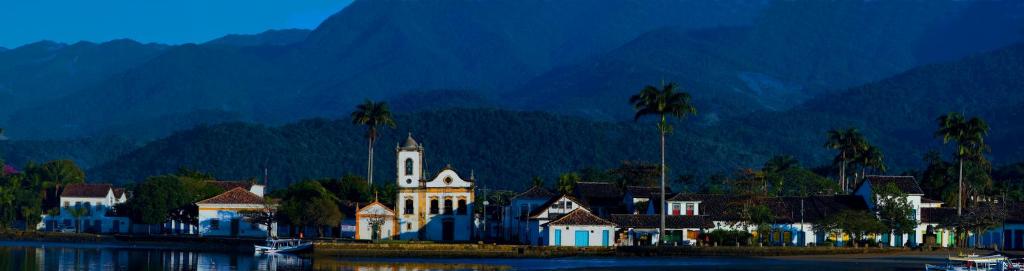 un edificio con palmeras frente a una montaña en Casa para temporada, en Paraty