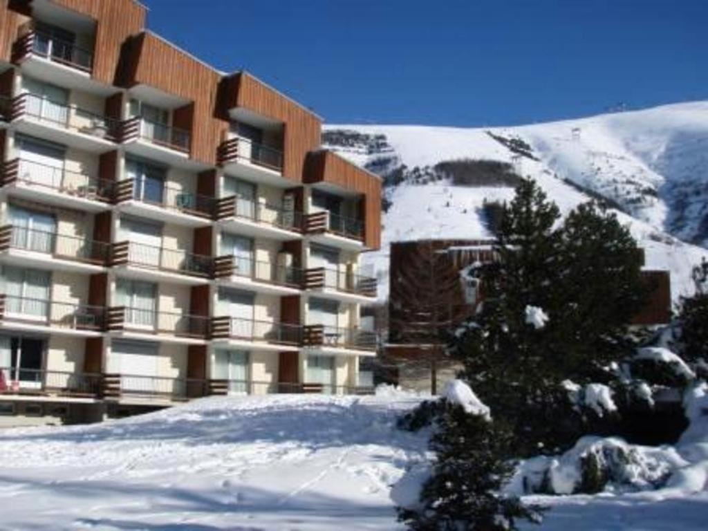 un grand immeuble dans la neige avec un arbre dans l'établissement Studio COTE BRUNE 2 ALPES, à Les Deux Alpes