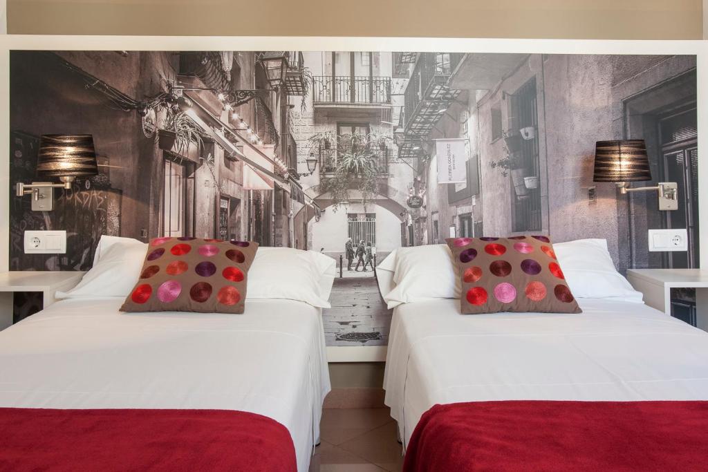 two beds in a room with a wall mural at BCNGOTIC 42 in Barcelona
