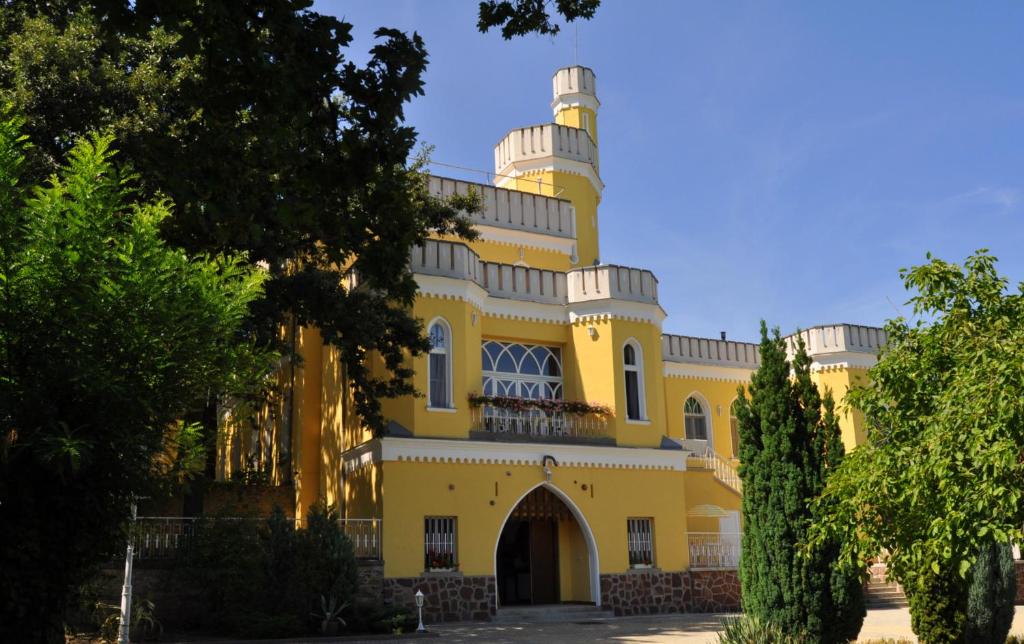 um edifício amarelo com uma torre em cima dele em Sir David Balaton Castle B&B em Balatonszepezd