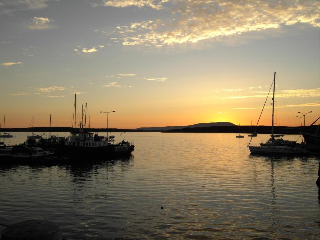 un grupo de barcos sentados en el agua al atardecer en The Puffin Baltimore, en Baltimore