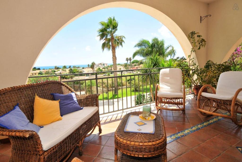 balcón con muebles de mimbre y vistas al océano en "Villa Rosa", en Marina di Ragusa