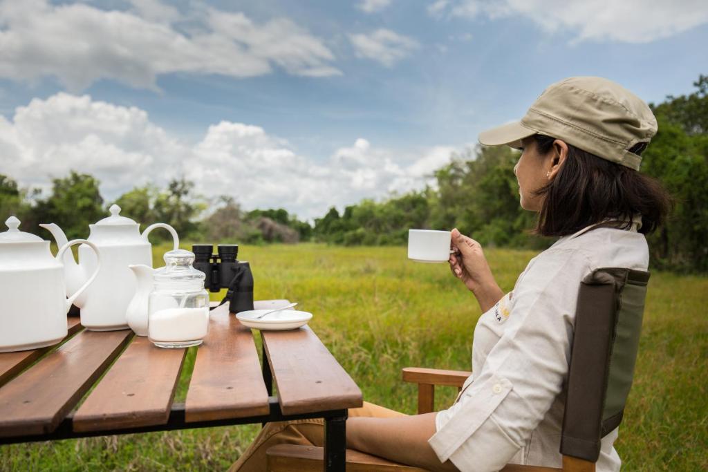 a woman sitting at a picnic table holding a cup at Mahoora Wilpattu - by Eco Team in Wilpattu