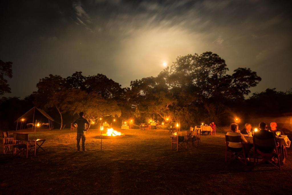 a group of people sitting around a fire at night at Mahoora Wilpattu - by Eco Team in Wilpattu