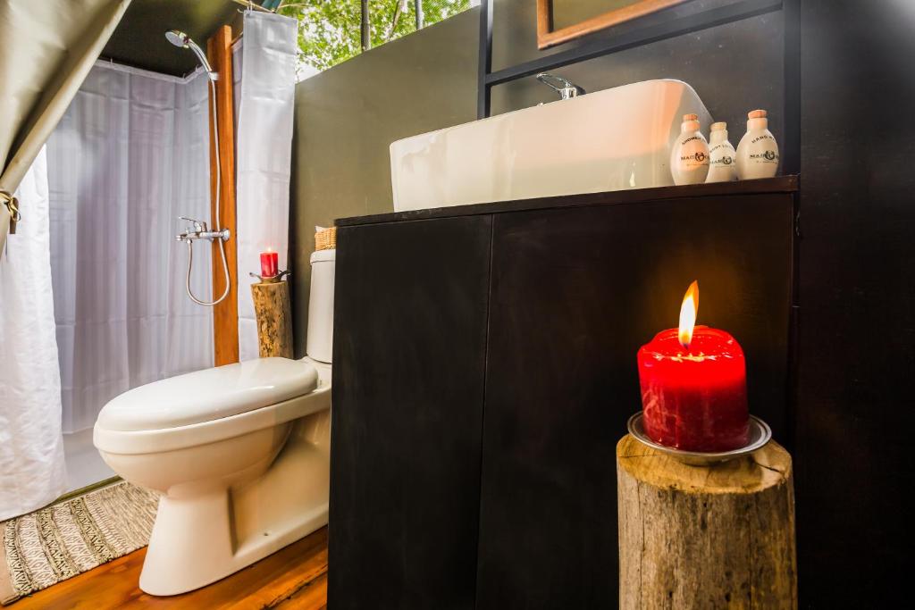 a bathroom with a red candle on a log at Mahoora Wilpattu - by Eco Team in Wilpattu