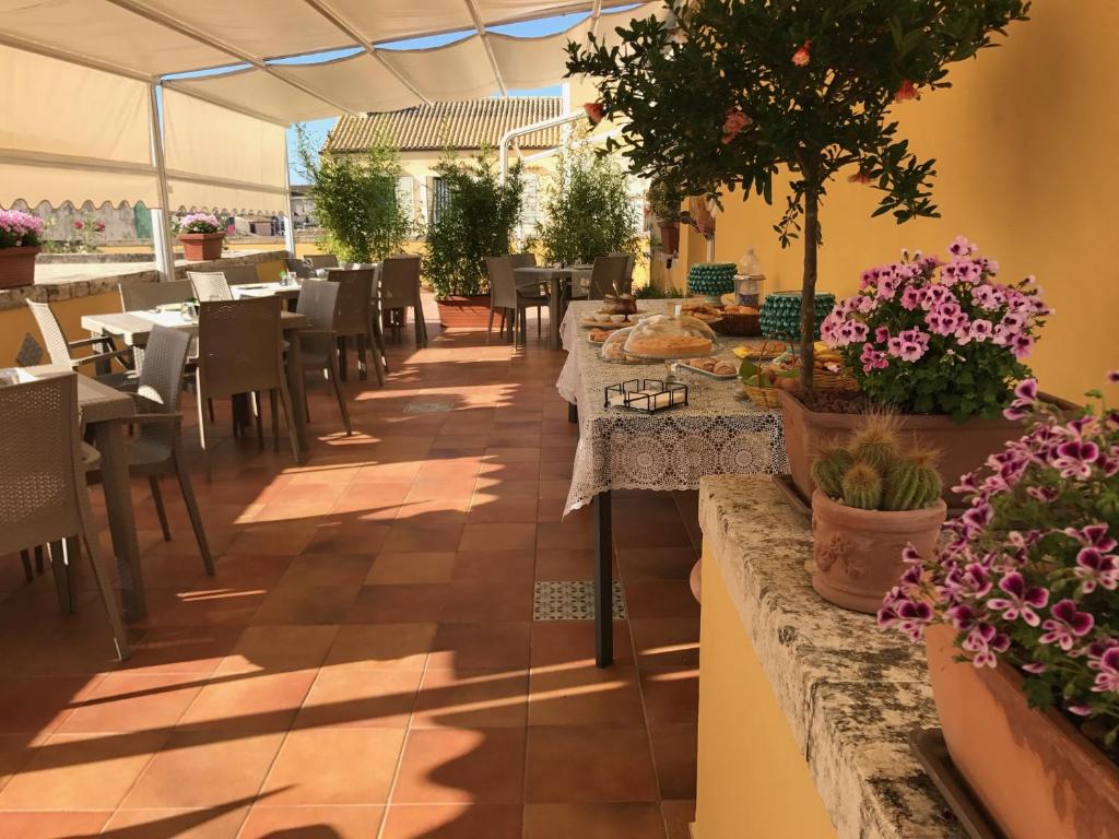ein Restaurant mit Tischen, Stühlen und Topfpflanzen in der Unterkunft I Santi Coronati in Syrakus