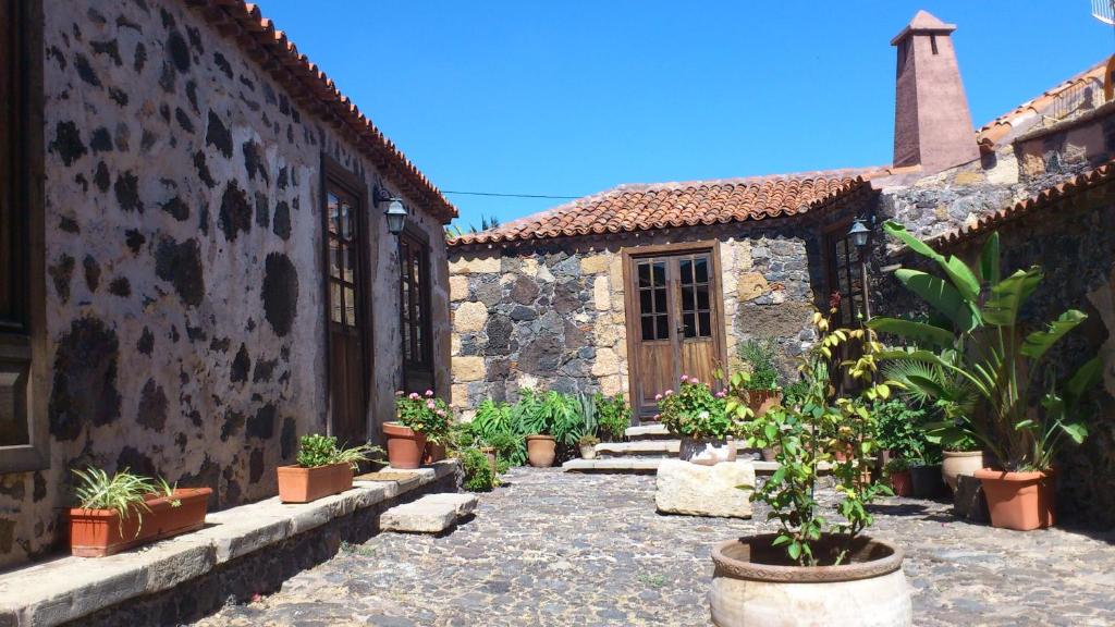 une cour d'un ancien bâtiment en pierre avec des plantes en pot dans l'établissement Casa Rural Vera De La Hoya, à San Miguel de Abona