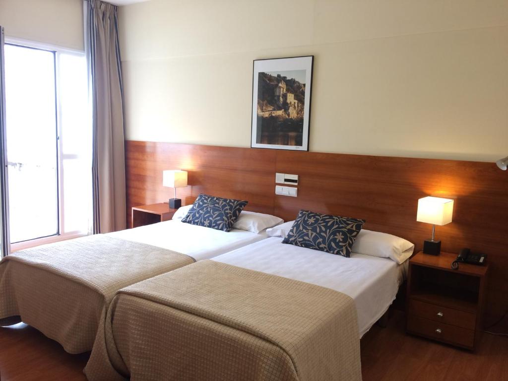 a hotel room with two beds and two lamps at Hotel Alda Ciudad de Soria in Soria