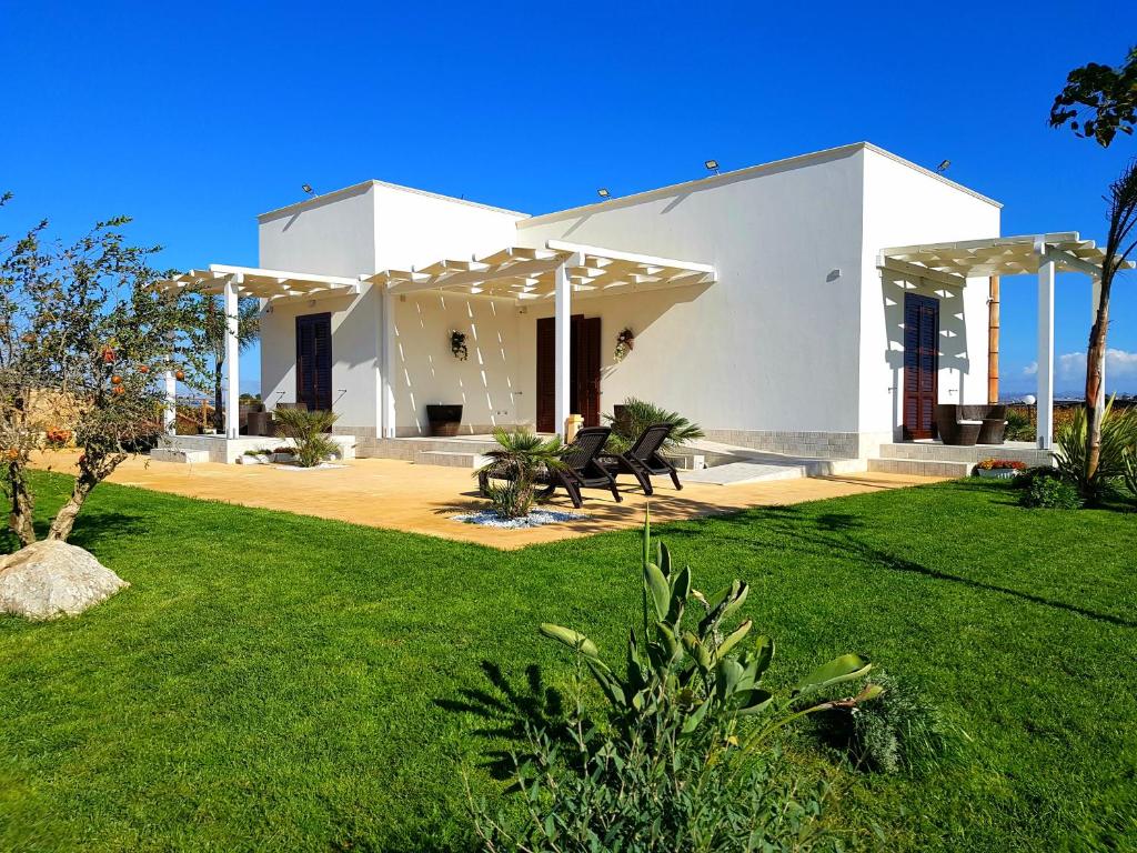 a white house with a green lawn in front of it at Villa Elios Guesthouse in Birgi Vecchi