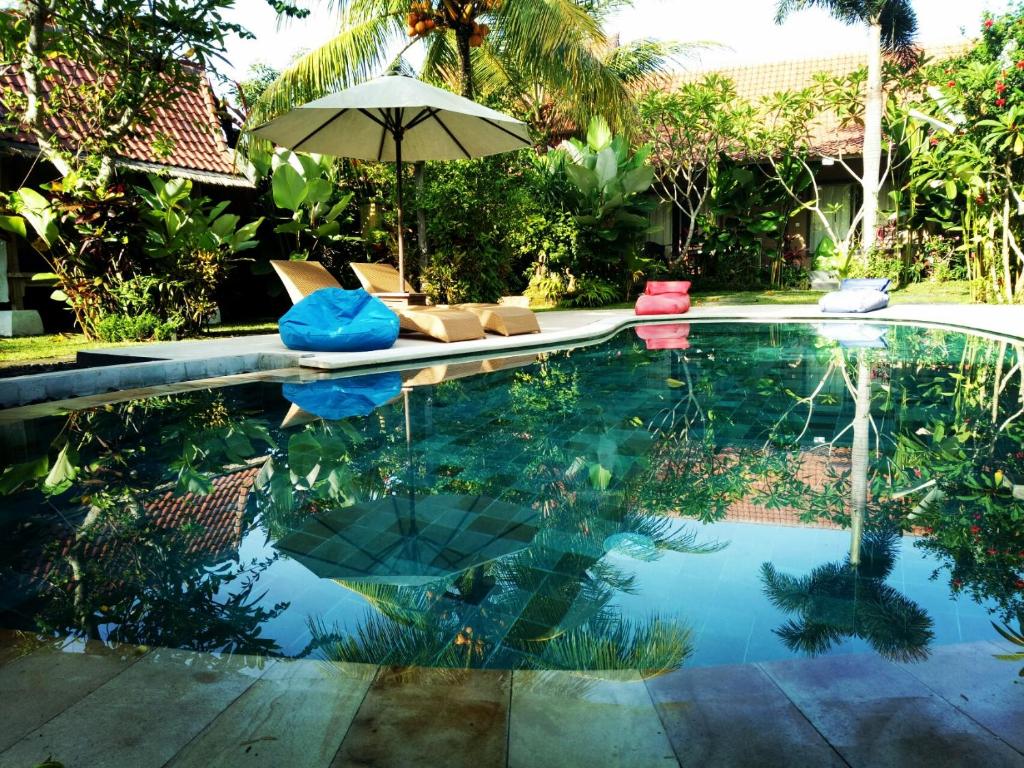 - une piscine avec un parasol et des chaises dans la cour dans l'établissement Baliwid Villa Ubud, à Ubud