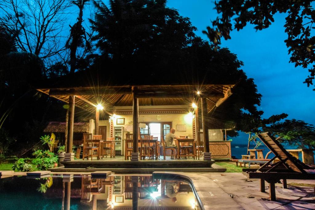 a house with a deck and a pool at night at Ganesha Amed in Amed