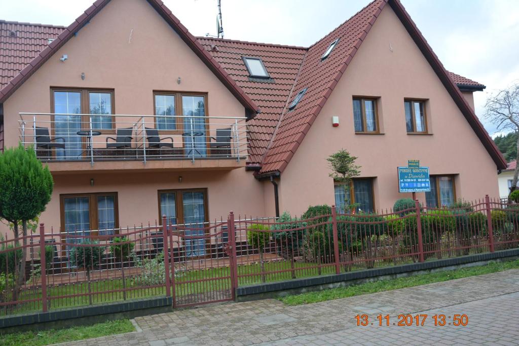 a pink house with a fence in front of it at Apartamenty i pokoje "U Dawida" in Mrzeżyno