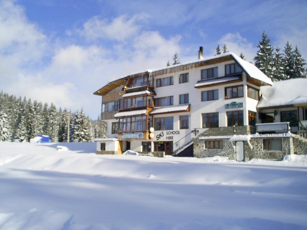 a large building in the snow with snow covered ground at Family Hotel Markony in Pamporovo