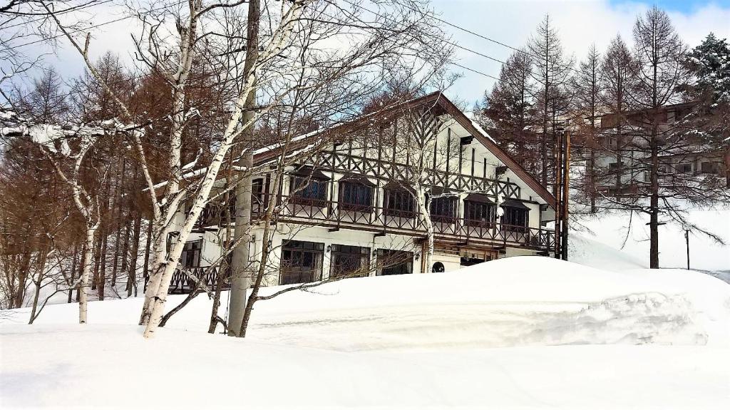 a house with a balcony in the snow at Chalet Madarao in Iiyama