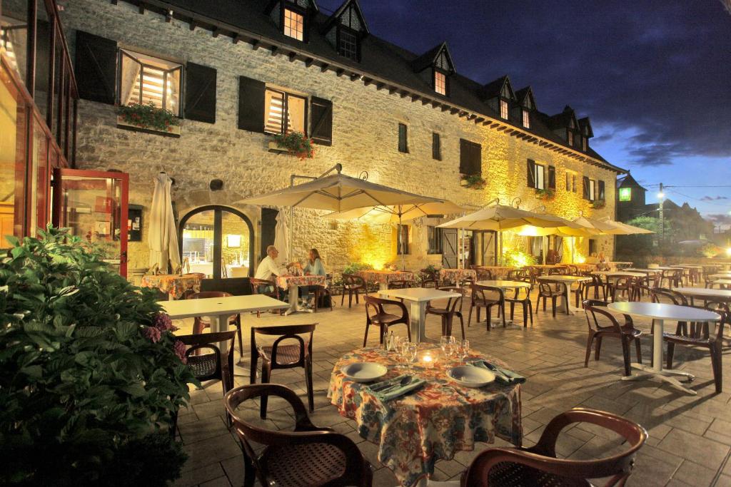 restauracja ze stołami i krzesłami przed budynkiem w obiekcie Logis Auberge La Diege w mieście Capdenac-Gare