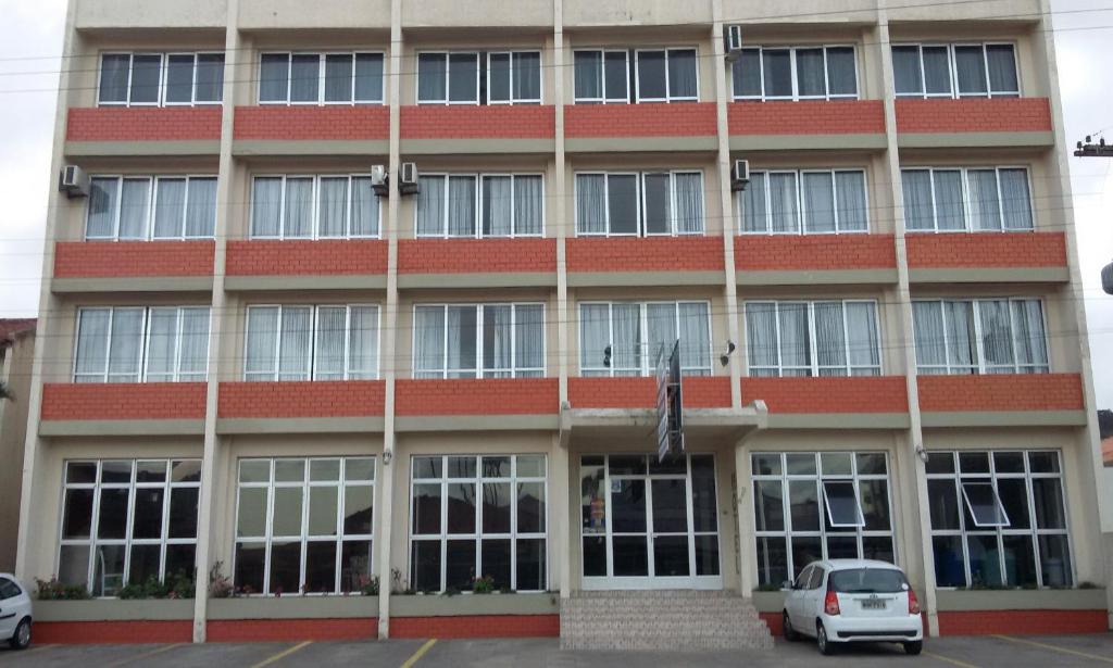 un gran edificio de ladrillo rojo con coches estacionados frente a él en Hotel Monte Líbano, en Laguna