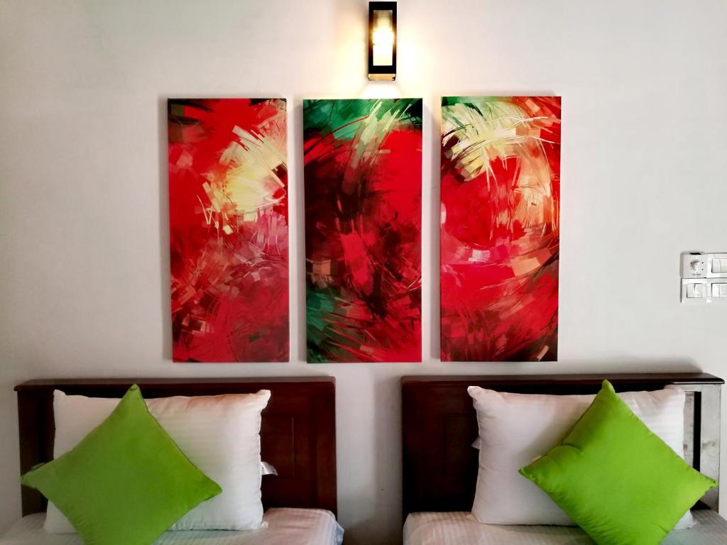 four paintings hanging on a wall above a bed at Villa A50 in Negombo