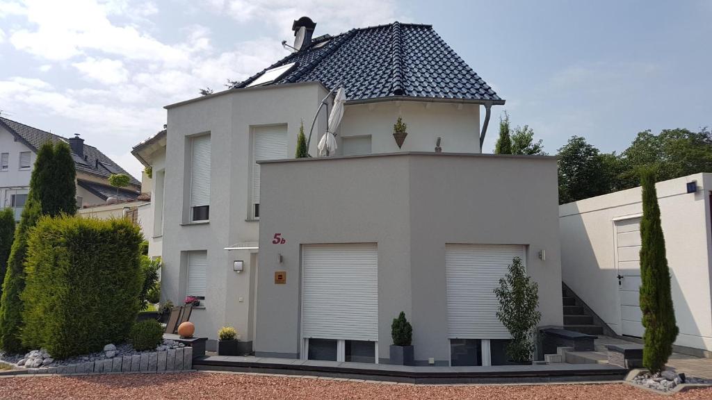 ein weißes Haus mit schwarzem Dach in der Unterkunft Pension Apartment Burscheid in Burscheid