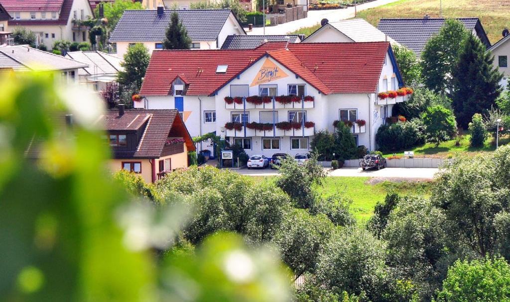 ein weißes Gebäude mit rotem Dach in einem Dorf in der Unterkunft Hotelpension Gästehaus Birgit in Bad Mergentheim