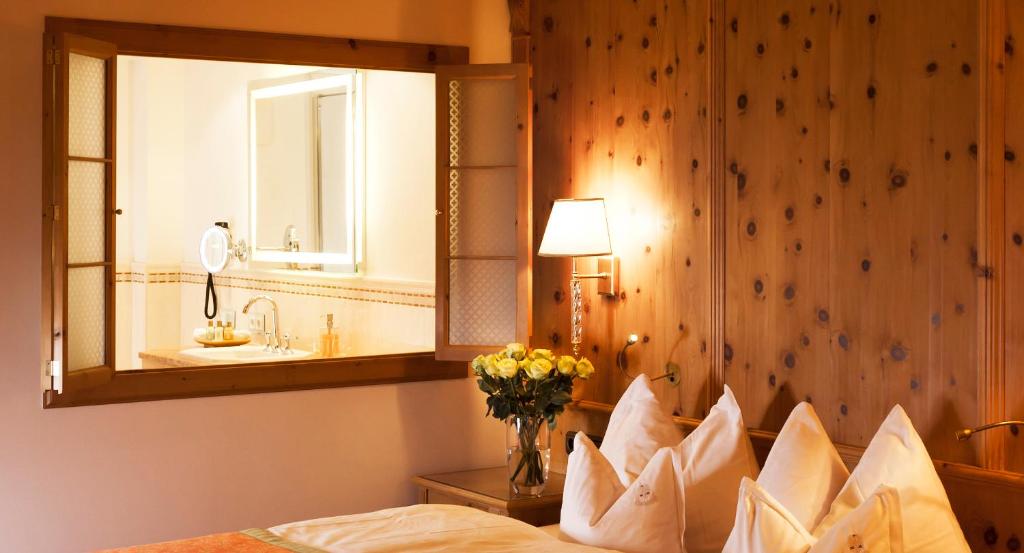a bedroom with a mirror and a bed with pillows at Superior Hotel Tirolerhof - Zell am See in Zell am See
