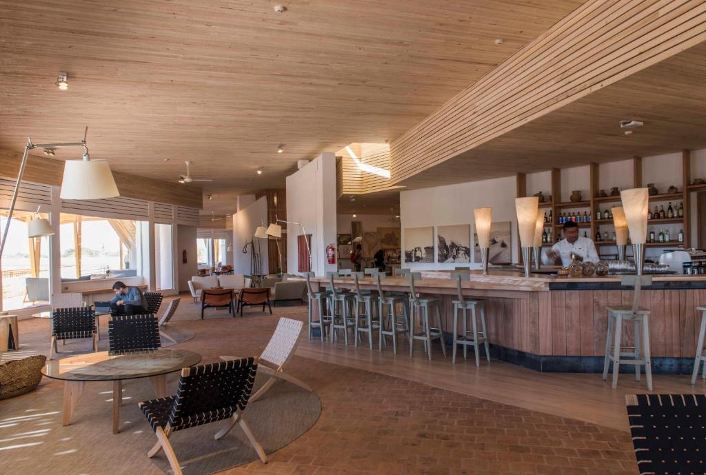 a restaurant with a bar with chairs and tables at Explora en Atacama - All Inclusive in San Pedro de Atacama