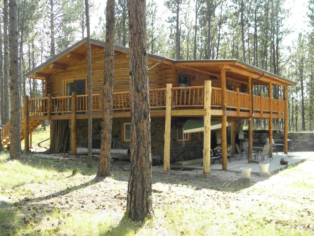 a large wooden cabin in the woods with trees at Trails End Lodge in Custer