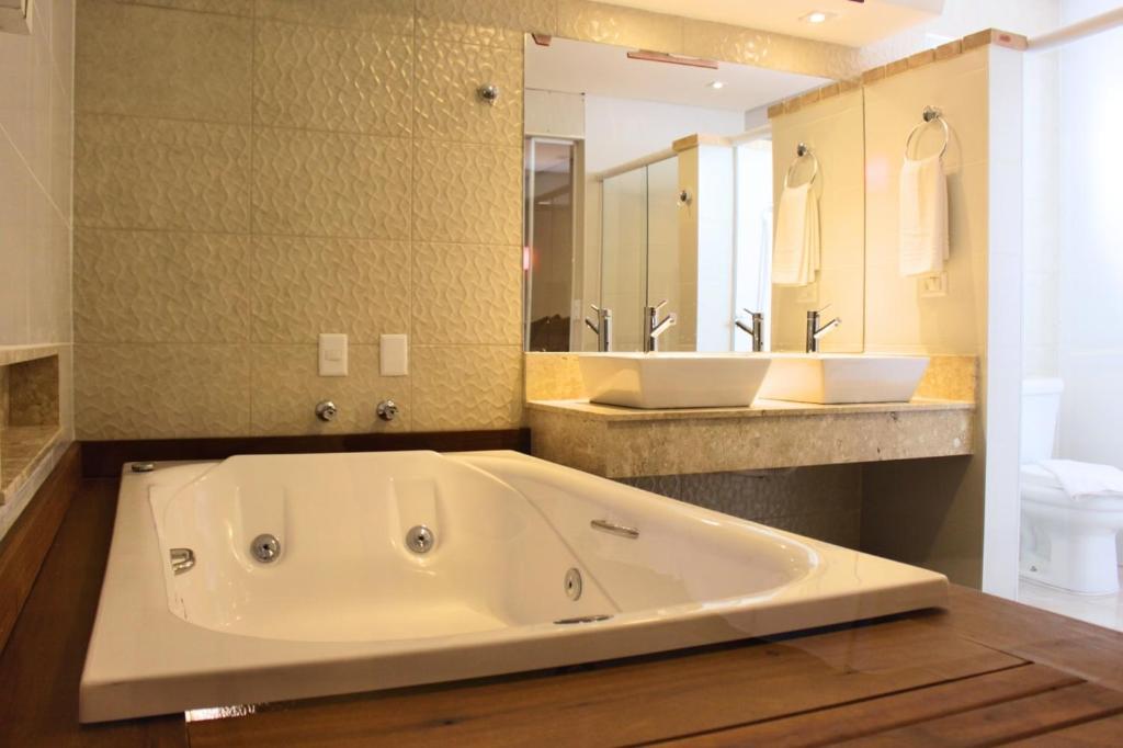 uma grande casa de banho com uma grande banheira e um lavatório em Don Marco's Hotel com Restaurante e Pizzaria no Guarujá