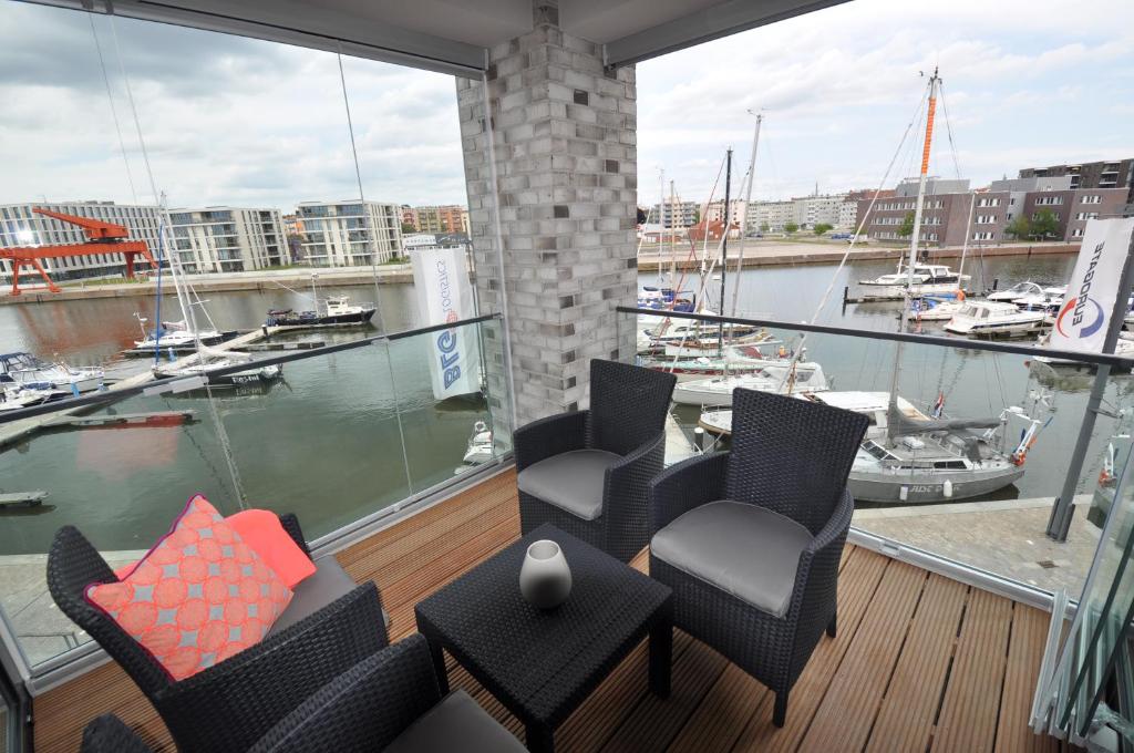 einen Balkon mit Stühlen und Blick auf den Yachthafen in der Unterkunft Apartment NewPort Bremerhaven in Bremerhaven