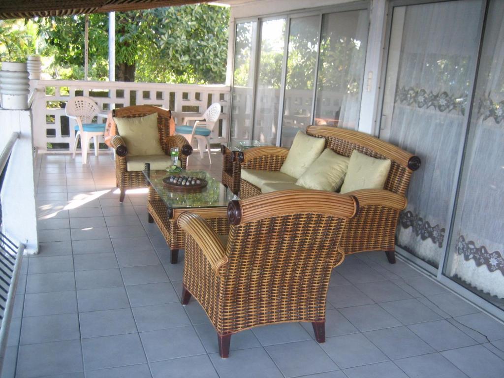 a screened porch with wicker chairs and a table at Farida Lodge in Moroni