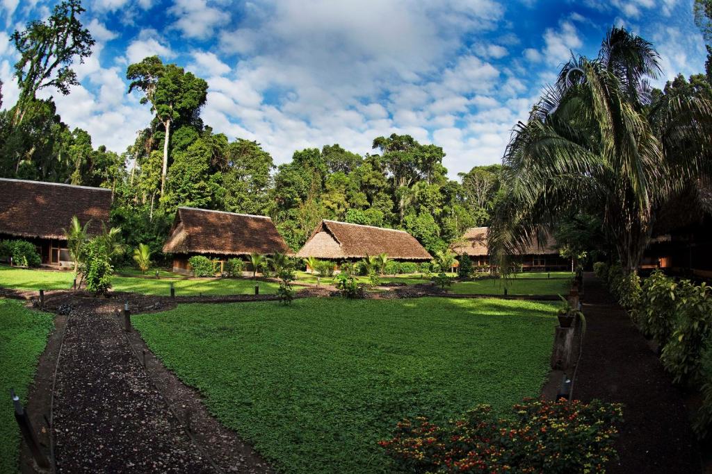einen grünen Hof mit Häusern und Bäumen im Hintergrund in der Unterkunft Amazon Field Station byInkaterra in Puerto Maldonado