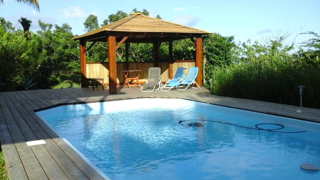 een zwembad met een tuinhuisje in de achtertuin bij Au Vieux Manguier in Deshaies